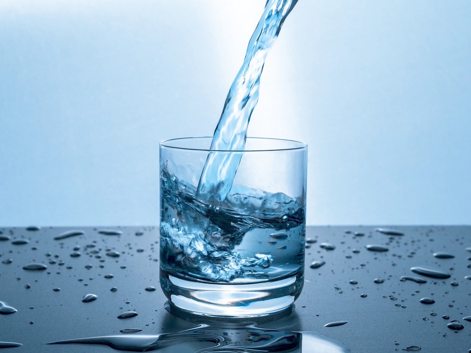 Ein Wasserglas wird mit klarem Wasser gefüllt
